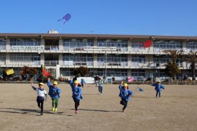 若狭野小学校の運動場で凧を持って走っている写真