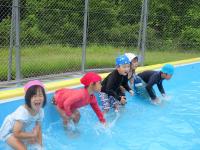 ４歳児がプールで体に水をかけている写真