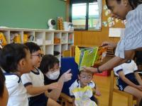 ４歳児が英語の先生から絵本を読んでもらっている写真