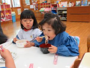 子どもが大きな口を開けておもちを食べている写真