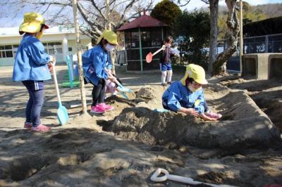 砂場でスコップを使ってお城の塀を作っているところ