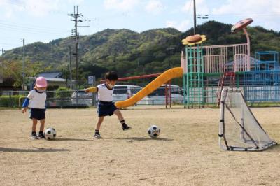 サッカーゴールに向かってボールを蹴っている写真