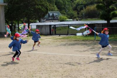 こいのぼりを持って走る4歳児