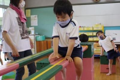 高い平均台をお尻をつけて座ったまま進んでいる写真