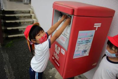 4歳児がハガキをポストに投函している写真