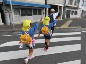 手をあげて横断歩道を渡っている写真