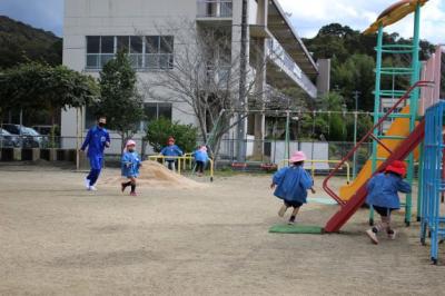 園庭でみんなで鬼ごっこをしている写真