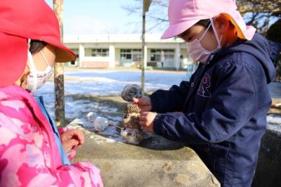 小さな雪だるまにどんぐり帽子をかぶせているところ