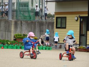5歳児と4歳児が三輪車で遊んでいる様子