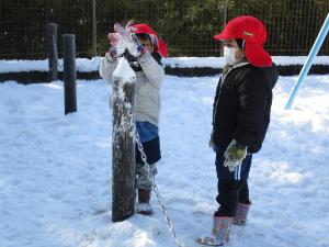 園児が雪遊びをする様子の写真