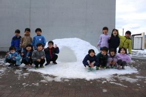 園児が雪遊びをする様子の写真