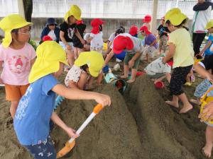 砂場で大きな砂山を作って水を流して遊んでいるところ