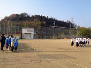 幼児が小学校のグラウンドでマラソン大会を応援している写真