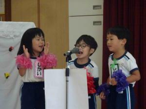 子ども3人がマイクの前で立っている写真