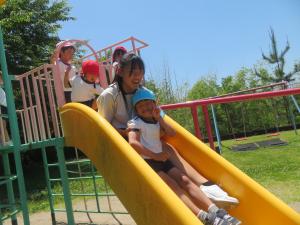 中学生と一緒に滑り台で遊んでいるところ