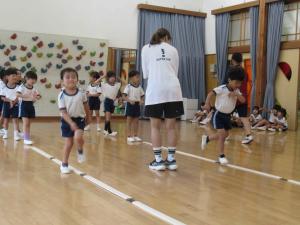 子ども達二人が先生に見守られながらジャンプをしている写真