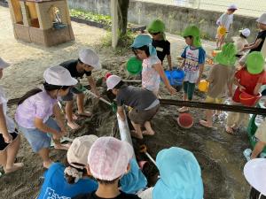 砂場で砂山を作ったり樋を使って水を流したりして遊んでいるところ