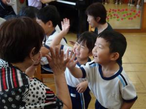 子どもがおばあちゃんと手を合わせている写真