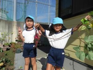 女の子が蔓のついたサツマイモを手に持っている写真