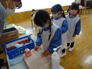 給食で、列に並んでお盆に牛乳やストローを乗せているところ