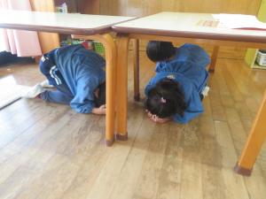 シェイクアウト訓練で机のしたに隠れているところ