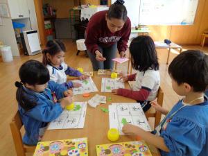 子ども達が座って紙を貼っている写真