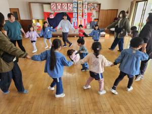 来年児を迎え、一緒に輪になって遊んでいる写真