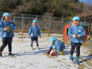 子ども達４人が雪合戦のための雪玉を作っている写真