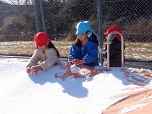 子ども二人が雪だるまを作っている写真