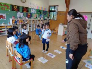 女の子がカードの前に立ち、先生と顔を合わせている写真