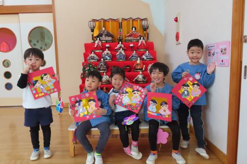 おひなさまの前で作った製作を持った写真