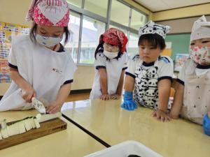 友達が野菜を切っている姿を見ている写真